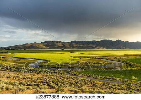 Stock Photo - River through fields by hills in Picabo, Idaho, USA. Fotosearch