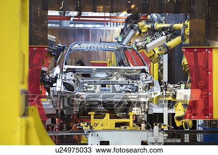 Stock Image - Robot laser welders with car body in car factory. Fotosearch