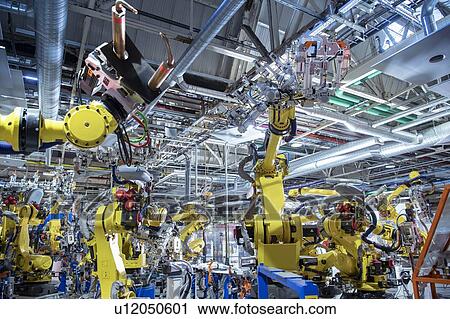 Stock Image - Robots spot welding car parts in car factory. Fotosearch