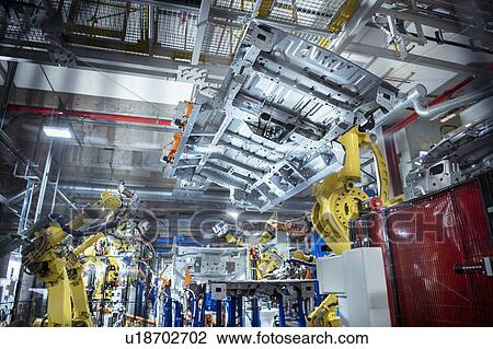 Stock Image - Robots spot welding car parts in car factory. Fotosearch