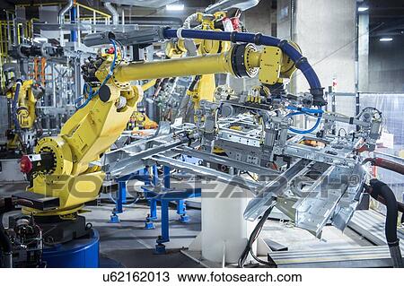 Stock Image - Robots spot welding car parts in car factory. Fotosearch