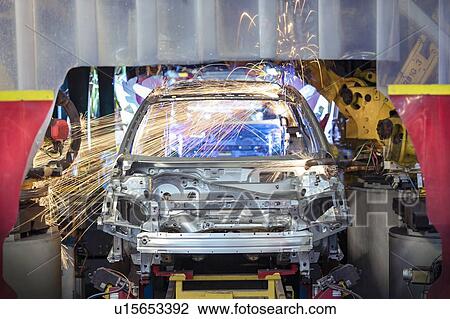 Stock Image - Robots welding steel car body in car factory. Fotosearch