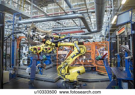 Stock Image - Robots with car body on production line in car factory. Fotosearch