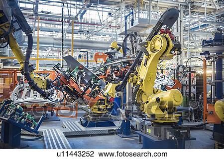 Stock Image - Robots with car body on production line in car factory. Fotosearch