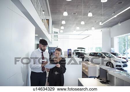 Salesman discussing contract with customer in car dealership View Large Photo Image Stock Photo - Salesman discussing contract with customer in car dealership. Fotosearch