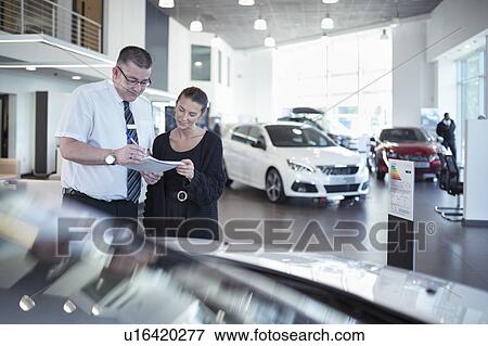 Salesman discussing contract with customer in car dealership View Large Photo Image Stock Photo - Salesman discussing contract with customer in car dealership. Fotosearch
