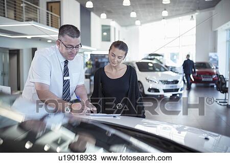 Salesman showing literature to customer in car dealership View Large Photo Image Stock Image - Salesman showing literature to customer in car dealership. Fotosearch