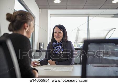 Saleswoman talking to customer in car dealership View Large Photo Image Picture - Saleswoman talking to customer in car dealership. Fotosearch