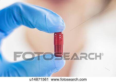 Stock Image - Scientist holding a red pill. Fotosearch