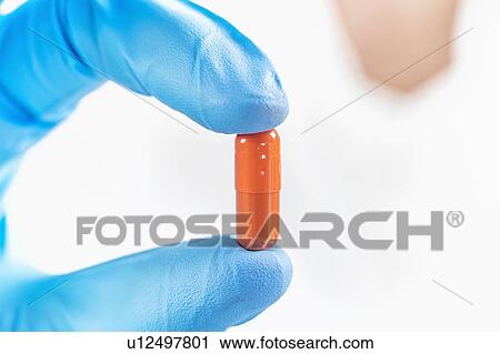 Scientist holding orange pill View Large Photo Image Stock Image - Scientist holding orange pill. Fotosearch