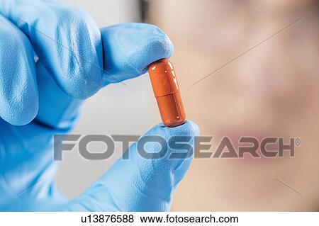Scientist holding orange pill View Large Photo Image Stock Photo - Scientist holding orange pill. Fotosearch