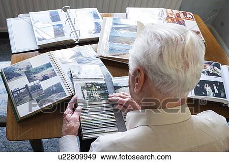 Senior man looking at photo albums View Large Photo Image Stock Photo - Senior man looking at photo albums. Fotosearch