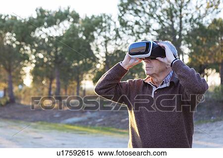 Stock Photography - Senior man wearing virtual reality simulator outdoors. Fotosearch