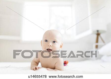 Stock Photo - Shirtless baby boy lying on bed. Fotosearch