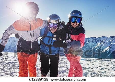 Stock Photo - Skiers, mother with teenage son and daughter with arms around each other on snow covered mountain top, portrait, Alpe-d'Huez, Rhone-Alpes, France. Fotosearch