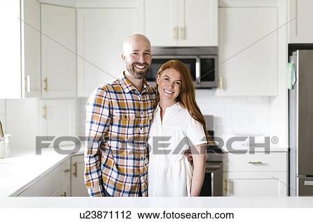 Stock Image - Smiling couple in kitchen. Fotosearch