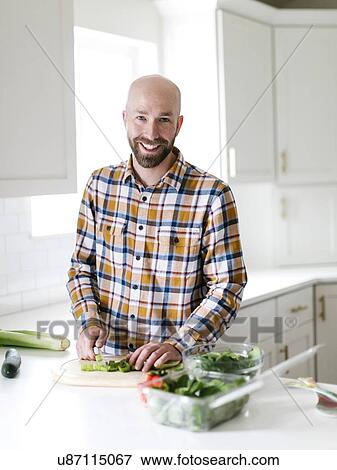Smiling man chopping vegetables in kitchen View Large Photo Image Stock Photo - Smiling man chopping vegetables in kitchen. Fotosearch