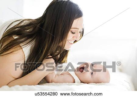 Smiling mother lying with her son on bed View Large Photo Image Stock Image - Smiling mother lying with her son on bed. Fotosearch