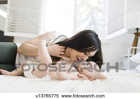 Stock Photography - Smiling mother lying with her son on bed. Fotosearch