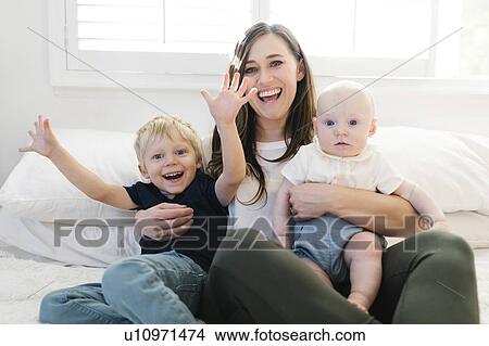 Smiling woman and her sons on bed View Large Photo Image Picture - Smiling woman and her sons on bed. Fotosearch