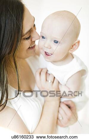 Stock Image - Smiling woman carrying her baby boy. Fotosearch