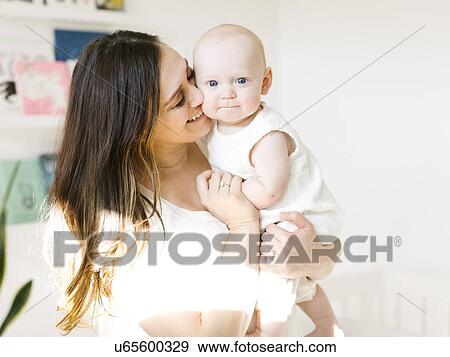Smiling woman carrying her baby boy View Large Photo Image Stock Photo - Smiling woman carrying her baby boy. Fotosearch