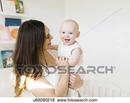 Stock Photo - Smiling woman carrying her baby boy. Fotosearch