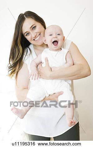 Stock Photograph - Smiling woman carrying her baby boy. Fotosearch