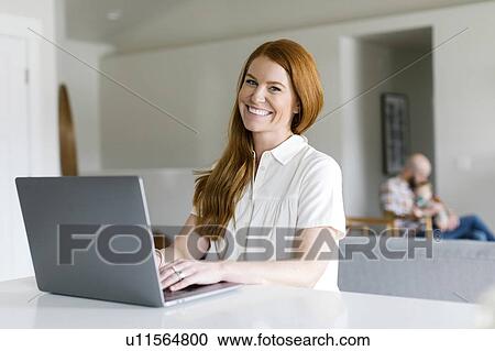 Smiling woman using laptop at home View Large Photo Image Stock Image - Smiling woman using laptop at home. Fotosearch
