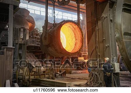 Stock Photograph - Steelworker inspecting inside of red hot, empty, steel flask in steelworks. Fotosearch