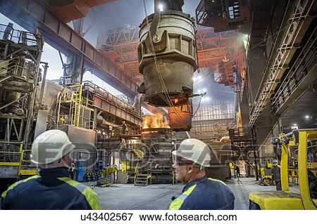 Stock Photo - Steelworkers making molten steel pour into vacuum mould in steelworks. Fotosearch