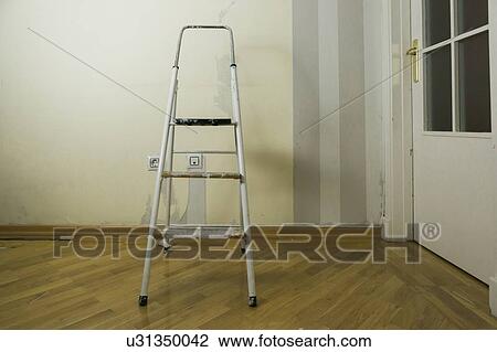 Stock Image - Step ladder by wall of torn wallpaper. Fotosearch