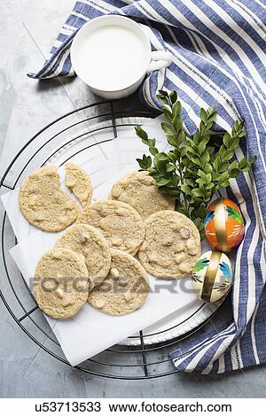 Stock Image - Still life of almond cookies on cooling rack with cup of milk, overhead view. Fotosearch