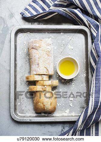 Still life of floured and unfloured ciabatta loaf on baking tray with bowl of olive oil, overhead view View Large Photo Image Stock Image - Still life of floured and unfloured ciabatta loaf on baking tray with bowl of olive oil, overhead view. Fotosearch