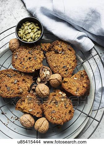 Picture - Still life of walnut and pumpkin seed cake sliced on cooling rack, overhead view. Fotosearch
