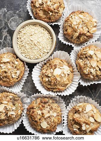 Stock Photograph - Still life of wholemeal muffins in cake cases with bowl of oats, overhead view. Fotosearch