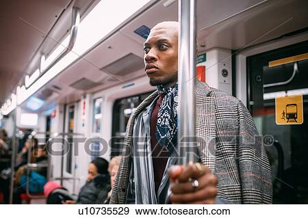 Stock Photo - Stylish man daydreaming in train, Milan, Italy. Fotosearch
