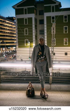 Stock Image - Stylish man leaning against bridge railings, Milan, Italy. Fotosearch