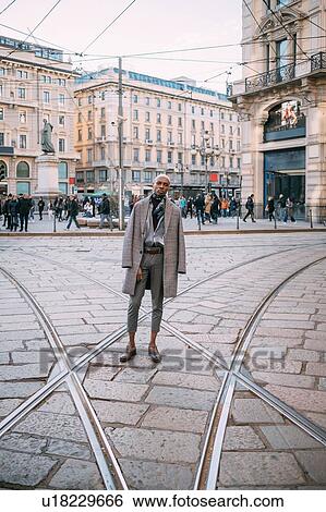 Stock Photograph - Stylish man posing on tram tracks in piazza, Milan, Italy. Fotosearch