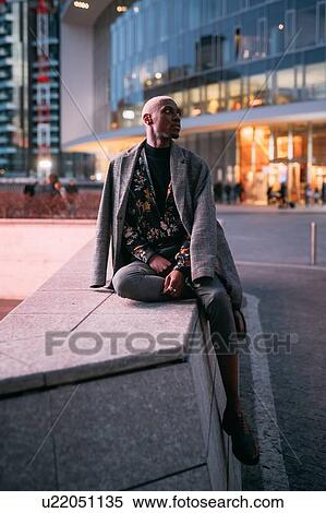 Stock Photography - Stylish man sitting on concrete bench, Milan, Italy. Fotosearch