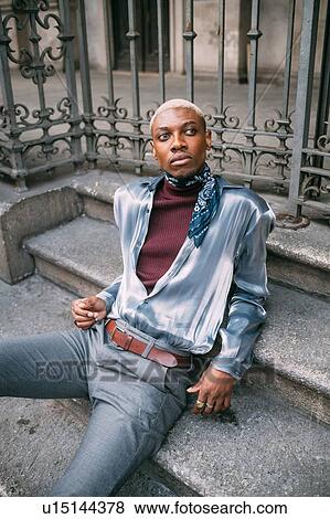 Stock Photo - Stylish man sitting on steps of period building, Milan, Italy. Fotosearch