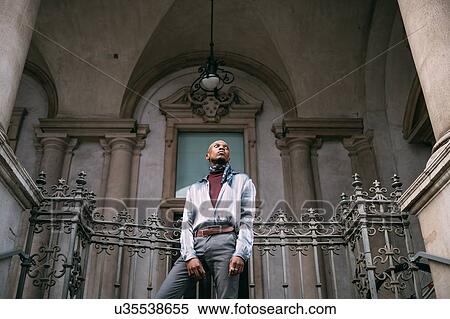 Stock Photography - Stylish man standing on steps of period building, Milan, Italy. Fotosearch