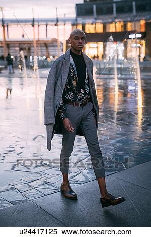 Stock Photography - Stylish man walking through piazza, water feature in background, Milan, Italy. Fotosearch