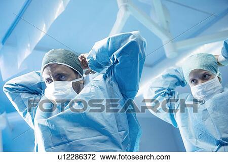 Stock Image - Surgeons gowning up. Fotosearch