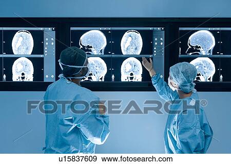 Stock Photo - Surgeons looking at MRI scans during surgery. Fotosearch