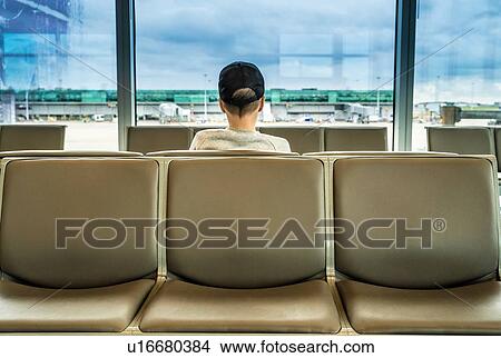 Teenage boy on seat looking out from airport departure lounge, rear view View Large Photo Image Picture - Teenage boy on seat looking out from airport departure lounge, rear view. Fotosearch