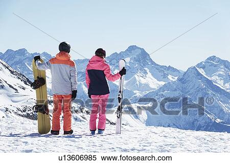 Teenage boy snowboarder with sister skier looking out from snow covered mountain top, rear view, Alpe-d'Huez, Rhone-Alpes, France View Large Photo Image Stock Photography - Teenage boy snowboarder with sister skier looking out from snow covered mountain top, rear view, Alpe-d'Huez, Rhone-Alpes, France. Fotosearch