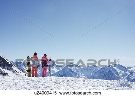 Teenage boy snowboarder with sister skier looking out from snow covered mountain top, rear view, Alpe-d'Huez, Rhone-Alpes, France View Large Photo Image Stock Photography - Teenage boy snowboarder with sister skier looking out from snow covered mountain top, rear view, Alpe-d'Huez, Rhone-Alpes, France. Fotosearch