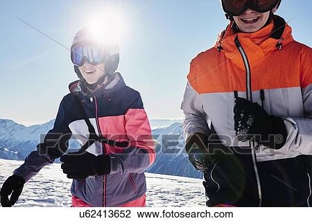 Stock Image - Teenage brother and sister skiers on snow covered mountain top, Alpe-d'Huez, Rhone-Alpes, France. Fotosearch