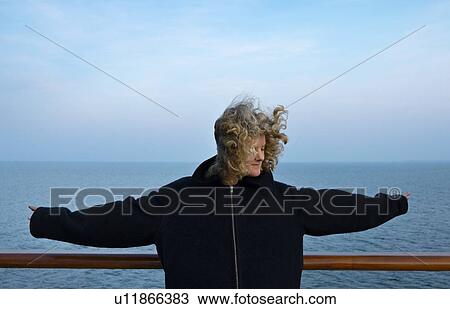 Stock Image - Teenage girl leaning against handrail on windy day. Fotosearch